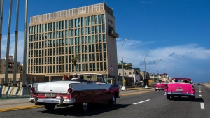 In this Oct. 3, 2017, file photo, tourists ride classic convertible cars on the Malecon beside the United States Embassy in Havana, Cuba. The Biden administration faces increasing pressure to respond to a sharply growing number of reported injuries suffered by diplomats, intelligence officers and military personnel that some suspect are caused by devices that emit waves of energy that disrupt brain function. The problem has been labeled the “Havana Syndrome,” because the first cases affected personnel in 2016 at the U.S. Embassy in Cuba. (AP Photo/Desmond Boylan, File)
