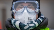 Dr. Lesley Seymour wears PPE, including an N95 respirator during a drive through COVID-19 vaccine clinic at St. Lawrence College in Kingston, Ont., Saturday, Dec. 18, 2021. THE CANADIAN PRESS/Lars Hagberg