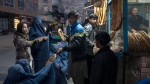 A man distributes bread to Burka-wearing Afghan women outside a bakery in Kabul, Afghanistan, Thursday, Dec, 2, 2021. UN World Food Program top official Mary-Ellen McGroarty says Afghanistan is facing a "tsunami of hunger," with the country on the verge of economic collapse and more than half of the population struggling to eat this winter. In an interview with The Associated Press on Thursday, Jan. 13, 2022 the WFP leader in Afghanistan urged the international community to separate political discussions from the humanitarian imperative by making sure the billions in aid that are required to avoid a disaster keep reaching the country, which is being run by the Taliban. (AP Photo/Petros Giannakouris, File)