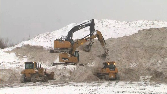 Heavy equipment piles up snow collected from around the city at a Toronto storage facility Monday, January 24, 2022. 