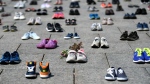 In this file photo, dried flowers rest inside a pair of child's running shoes at a memorial for the 215 children whose remains were found at the grounds of the former Kamloops Indian Residential School at Tk’emlups te Secwépemc First Nation in Kamloops, B.C., on Parliament Hill in Ottawa on Friday, June 4, 2021. THE CANADIAN PRESS/Justin Tang 