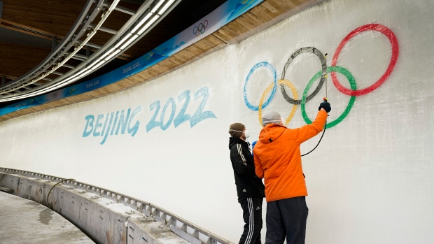 Two ice makers spray water after installing a sub-glacial Beijing 2022 logo on the track at the Yanqing National Sliding Center ahead of the 2022 Winter Olympics, Friday, Jan. 28, 2022, in the Yanqing district of Beijing. (AP Photo/Jae C. Hong)