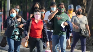 People wearing mask to prevent the spread of the coronavirus walks beside a street in Quezon city, Philippines on Monday, Jan. 17, 2022. (AP Photo/Aaron Favila) 