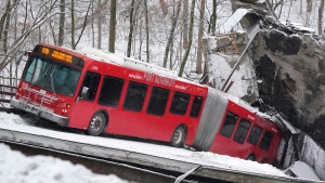 A Port Authority bus that was on a bridge when it collapsed Friday Jan. 28, 2022, is visible in Pittsburgh's East End. When the bridge collapsed, rescuers rappeled nearly 150 feet while others formed a human chain to help rescue multiple people from the dangling bus. (AP Photo/Gene J. Puskar)