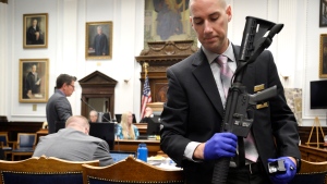 FILE - Kenosha Police Department Detective Martin Howard, right, picks up the weapon Kyle Rittenhouse used on Aug. 25, 2020, during Rittenhouse's trial at the Kenosha County Courthouse in Kenosha, Wis., on Nov. 8, 2021. A Wisconsin judge is set to hear arguments Friday, Jan. 28, 2022, on whether prosecutors should return the assault-style rifle Rittenhouse used to shoot three people during a street protest back to him. (Sean Krajacic/The Kenosha News Pool Photo via AP, File)