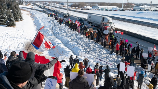 Hundreds of people gather by TransCanada Highway 20 to show their support to truckers heading to Ottawa to protest against COVID-19 restrictions, Friday, Jan. 28, 2022 in Levis, Que. THE CANADIAN PRESS/Jacques Boissinot 