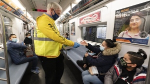 FILE - Patrick Foye, Chairman and CEO of the Metropolitan Transportation Authority, hands out face masks on a New York City subway, , Nov. 17, 2020, in New York. The Centers for Disease Control and Prevention is developing guidance that will ease the nationwide mask mandate for public transit next month. That's according to a U.S. official. (AP Photo/Mark Lennihan, File)