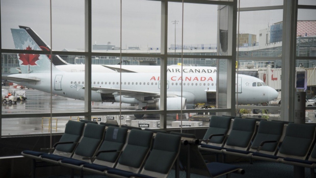 A plane is seen through the window on the tarmac of Vancouver International Airport as the waiting room is empty Tuesday, June 9, 2020. Air Canada says it is suspending flights between Vancouver and Delhi this summer due to extended flying times and a refueling stop that are needed to avoid Russian and Ukraine airspace. THE CANADIAN PRESS/Jonathan Hayward