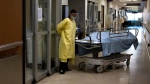 A health-care worker leaves the room with a deceased COVID-19 patient transferring them to the hospital morgue in the intensive care unit at the Humber River Hospital during the COVID-19 pandemic in Toronto on Tuesday, January 25, 2022. THE CANADIAN PRESS/Nathan Denette