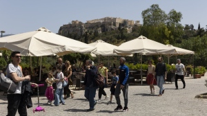 People make their way on a pedestrian street at the foot of the Acropolis hill, in Athens, on Sunday, May 1, 2022. Italy and Greece relaxed some COVID-19 restrictions on Sunday, in a sign that life was increasingly returning to normal before Europe's peak summer tourist season. (AP Photo/Yorgos Karahalis)