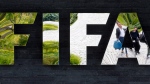 In this May 27, 2015, file photo, two persons are reflected in the FIFA logo at the FIFA headquarters in Zurich, Switzerland. (AP Photo/Michael Probst)