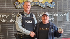 Cst. Mike Della-Paolera returns a stolen hockey card to Ian Moore in a Kelowna RCMP handout photo. A Wayne Gretzky rookie card that was stolen seven years ago in West Kelowna, B.C., is now back in the hands of its owner. Mounties say the card landed in their exhibits file in 2019, but it was only returned to owner Moore when it came up for disposal and the officer who investigated the original theft put the pieces together. THE CANADIAN PRESS/HO-Kelowna RCMP **MANDATORY CREDIT**