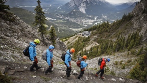 Guide Eli Schellenberg, in red, leads climbers down from the summit of the Mt. Norquay Via Ferrata near Banff, Alta., Thursday, June 20, 2019. Even as gas prices hit record highs, Canadians are fanning out across the country for fresh travel experiences after two years of bottled-up demand. THE CANADIAN PRESS/Jeff McIntosh