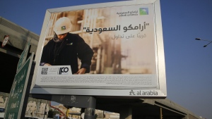 FILE - A man walks under a billboard displaying an advertisement for Saudi Arabia's state-owned oil giant Aramco with Arabic reading "Saudi Aramco, soon on stock exchange" in Jiddah, Saudi Arabia on Nov. 12, 2019. Oil giant Saudi Aramco said Sunday, May 15, 2022 its profits soared more than 80% in the first three months of the year, as the state-backed company cashes in on the volatility in global energy markets and soaring oil prices following Russia’s invasion of Ukraine. (AP Photo/Amr Nabil, File)