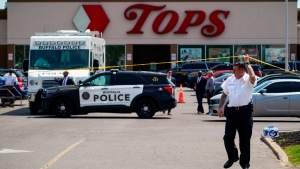 A police officer lifts the tape cordoning off the scene of a shooting at a supermarket, in Buffalo, N.Y., Sunday, May 15, 2022. A white 18-year-old wearing military gear and livestreaming with a helmet camera opened fire with a rifle at a supermarket in Buffalo, killing and wounding people in what authorities described as â€œracially motivated violent extremism.â€ (AP Photo/Matt Rourke)