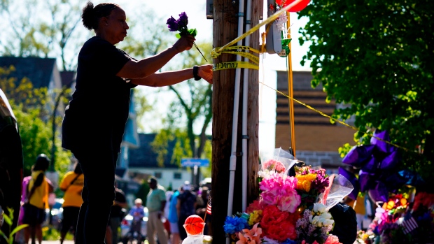 A person tends to a makeshift memorial outside the scene of a shooting at a supermarket the day before, in Buffalo, N.Y., Sunday, May 15, 2022. (AP Photo/Matt Rourke)