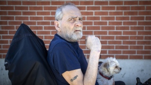 Will Towell holds his miniature terrier on his lap outside his temporary housing in Kingston, Ont., on Monday May 9, 2022.THE CANADIAN PRESS/Lars Hagberg