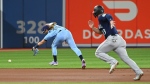 Toronto Blue Jays' Bo Bichette, left, misses a ground ball off the bat of Seattle Marinersâ€™ Eugenio Suarez, advancing Ty France, right, in the first inning of an American League baseball game in Toronto on Wednesday, May 18, 2022. THE CANADIAN PRESS/Jon Blacker