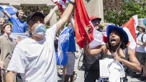 Anti-Bill 96 protesters hold up a Canadian flag as a Bill 96 supporter shouts during a demonstration in Montreal, Saturday, May 14, 2022. THE CANADIAN PRESS/Graham Hughes