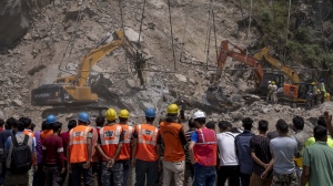 Rescue workers watch from a distance as earth movers dig through rubble of a collapsed tunnel in Ramban district, south of Srinagar, Indian controlled Kashmir, Friday, May 20, 2022. An official in Indian-controlled Kashmir said Friday that 10 workers were trapped after part of a road tunnel collapsed in the Himalayan region. (AP Photo/Dar Yasin)