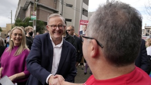 Labor Party leader Anthony Albanese, center, shakes hands with a voter he and his partner Jodie Haydon, left, arrive a polling place to cast their ballots in Sydney, Australia, Saturday, May 21, 2022. Australians go to the polls following a six-week election campaign that has focused on pandemic-fueled inflation, climate change and fears of a Chinese military outpost being established less than 1,200 miles off Australia's shore. (AP Photo/Rick Rycroft)