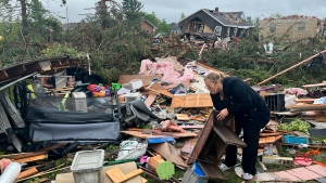 Theresa Haske sorts through debris from what was her garage after a tornado tore through Gaylord, Mich., Friday, May 20, 2022. (AP Photo/John Russell)