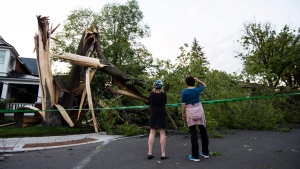 Residents take a look at a tree that was destroyed during a major storm in Ottawa on Saturday, May 21, 2022. THE CANADIAN PRESS/Justin Tang