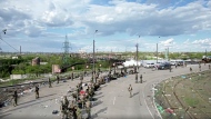 In this photo taken from video released by the Russian Defense Ministry on Saturday, May 21, 2022, Ukrainian servicemen line up to be checked as they leave the besieged Azovstal steel plant in Mariupol, in territory under the government of the Donetsk People's Republic, eastern Ukraine. (Russian Defense Ministry Press Service via AP)