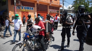 Residents flee their home on a motorbike to avoid clashes between armed gangs in La Plaine neighborhood of Port-au-Prince, Haiti, Friday, May 6, 2022.  Fighting rages in four districts on the northern side of Port-au-Prince that has surged as increasingly powerful gangs try to control more territory during the political power vacuum left by the July 7 assassination of President Jovenel Moise. (AP Photo/Odelyn Joseph)