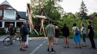 Community members gather to look at a tree that was destroyed during a major storm in Ottawa on Saturday, May 21, 2022. THE CANADIAN PRESS/Justin Tang