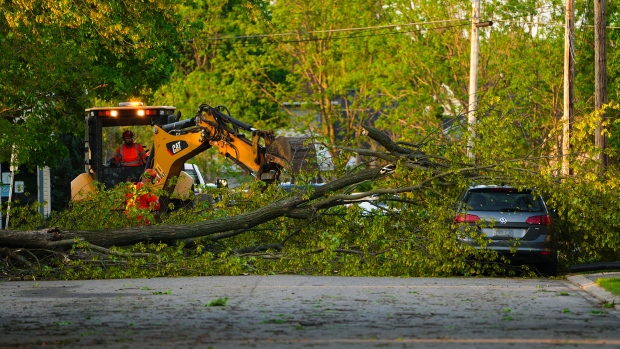 Crews remove a tree from a car following  a major storm in Carleton Place, Ont. on Saturday, May 21, 2022. THE CANADIAN PRESS/Sean Kilpatrick