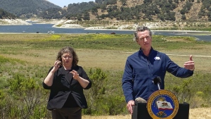FILE - In this July 8, 2021, file photo, California Gov. Gavin Newsom and sign interpreter Julia Townsend stand at the edge of a diminished Lopez Lake near Arroyo Grande, Calif. Newsom threatened Monday, May 23, 2022, to impose mandatory, statewide restrictions on water use if people don't start using less on their own as the drought drags on and the hotter summer months approach. (David Middlecamp/The Tribune of San Luis Obispo via AP, File)