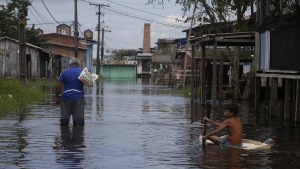 A boy uses a fridge door to float across a street flooded by the rise of the Negro river in Iranduba, Amazonas state, Brazil, Monday, May 23, 2022. The Amazon region is being hit hard by flooding with 35 municipalities that are facing one of their worst floods in years and the water level is expected to rise over the coming months. (AP Photo/Edmar Barros)