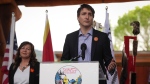 Prime Minister Justin Trudeau speaks as Tk’emlúps te Secwépemc Kúkpi7 (Chief) Rosanne Casimir, back left, listens during a ceremony marking the one-year anniversary of the announcement of the detection of the remains of 215 children at an unmarked burial site at the former Kamloops Indian Residential School, in Kamloops, B.C., on Monday, May 23, 2022. THE CANADIAN PRESS/Darryl Dyck