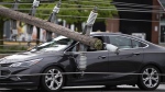 A motorist remains in their vehicle as they wait for crews to make sure they can leave safely, after power lines and utility poles came down onto their car during a major storm, on Merivale Road in Ottawa, on Saturday, May 21, 2022.  THE CANADIAN PRESS/Justin Tang