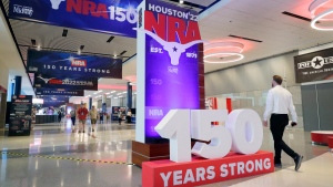 People walk past signage in the hallways outside of the exhibit halls at the NRA Annual Meeting held at the George R. Brown Convention Center Thursday, May 26, 2022, in Houston. (AP Photo/Michael Wyke)