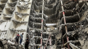 In this photo provided by Tasnim News Agency, debris hangs from the Metropol buildin,g a 10-story commercial building under construction, in the southwestern city of Abadan, Iran, Tuesday, May 24, 2022. Rescuers dug through debris Tuesday of the collapsed building that killed at least 11 people, fearful that many more could still be trapped beneath the rubble as authorities arrested the city's mayor in a widening probe of the disaster. (Hossein Abdollah Asl, Tasnim News Agency via AP)