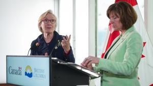 Federal Minister of Mental Health and Addictions and Associate Minister of Health Carolyn Bennett, back left, speaks as B.C. Minister of Mental Health and Addictions Sheila Malcolmson listens during a news conference after British Columbia was granted an exemption to decriminalize possession of some illegal drugs for personal use, in Vancouver, on Tuesday, May 31, 2022. THE CANADIAN PRESS/Darryl Dyck