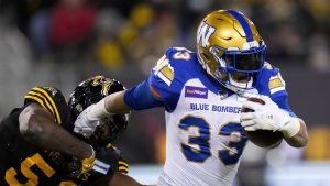 Winnipeg Blue Bombers running back Andrew Harris (33) evades a tackle from Hamilton Tiger-Cats defensive end Ja'Gared Davis (56) during first half football action in the 108th CFL Grey Cup in Hamilton, Ont., on Sunday, December 12, 2021. THE CANADIAN PRESS/Nathan Denette