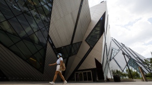 A person wearing a mask walks by the Royal Ontario Museum in Toronto, on Friday, June 26, 2020. The Royal Ontario Museum will allow visitors into its main floor for free this summer in an effort to draw crowds. Starting June 9 and running through Sept. 25, 2022, the first floor galleries will be accessible to the public without a fee. THE CANADIAN PRESS/Cole Burston