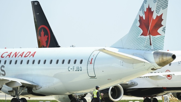 Airline ground crew walks past grounded Air Canada planes as they sit on the tarmac at Pearson International Airport, in Toronto on Tuesday, April 27, 2021. Half a million passengers sat aboard delayed international flights at Pearson in May. THE CANADIAN PRESS/Nathan Denette