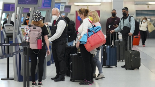 People wait in line to check in at Pearson International Airport in Toronto on Thursday, May 12, 2022. Canada's transport regulator is beefing up passenger protection rules, placing more stringent rules around reimbursement by airlines. THE CANADIAN PRESS/Nathan Denette