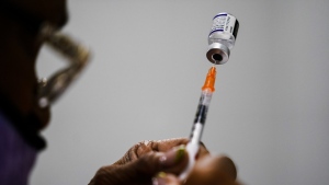FILE - A syringe is prepared with the Pfizer COVID-19 vaccine at a vaccination clinic at the Keystone First Wellness Center in Chester, Pa., Dec. 15, 2021. Pfizer says tweaking its COVID-19 vaccine to better target the omicron variant is safe and boosts protection. Saturday, June 25, 2022 announcement comes just days before regulators debate whether to offer Americans updated booster shots this fall. (AP Photo/Matt Rourke, File)