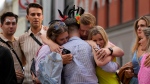 People comfort each other as they stand at the scene of a shooting in central Oslo, Norway, Saturday, June 25, 2022. (AP Photo/Sergei Grits)