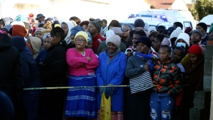 People stand behind a police cordon outside a nightclub in East London, South Africa, Sunday June 26, 2022. South African police are investigating the deaths of at least 20 people at a nightclub in the coastal town of East London early Sunday morning. It is unclear what led to the deaths of the young people, who were reportedly attending a party to celebrate the end of winter school exams. (AP Photo)