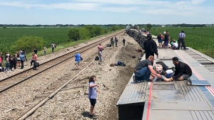 In this photo provided by Dax McDonald, an Amtrak passenger train lies on its side after derailing near Mendon, Mo., on Monday, June 27, 2022. The Southwest Chief, traveling from Los Angeles to Chicago, was carrying about 243 passengers when it collided with a dump truck near Mendon, Amtrak spokeswoman Kimberly Woods said. (Dax McDonald via AP)