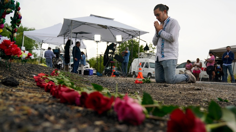 Carlow Eduardo Espina prays after placing roses on a make-shift memorial at the site where officials found dozens of people dead in a semitrailer containing suspected migrants, Tuesday, June 28, 2022, in San Antonio. (AP Photo/Eric Gay)