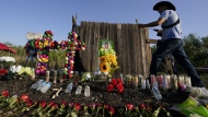 Roberto Marquez of Dallas adds a flower a makeshift memorial at the site where officials found dozens of people dead in an abandoned semitrailer containing suspected migrants, Wednesday, June 29, 2022, in San Antonio. (AP Photo/Eric Gay)