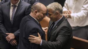 Israeli Prime Minister Naftali Bennett, left, and Foreign Minister Yair Lapid react after a vote on a bill to dissolve the parliament at the Knesset, Israel's parliament, in Jerusalem, Thursday, June 30, 2022. Israel's parliament has voted to dissolve itself, sending the country to the polls for the fifth time in less than four years. (AP Photo/Ariel Schalit)