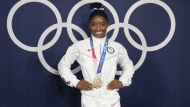FILE - Simone Biles, of the United States, poses wearing her bronze medal from balance beam competition during artistic gymnastics at the 2020 Summer Olympics, Aug. 3, 2021, in Tokyo, Japan. President Joe Biden will present the nation’s highest civilian honor, the Presidential Medal of Freedom, to 17 people, at the White House next week. (AP Photo/Natacha Pisarenko, File)